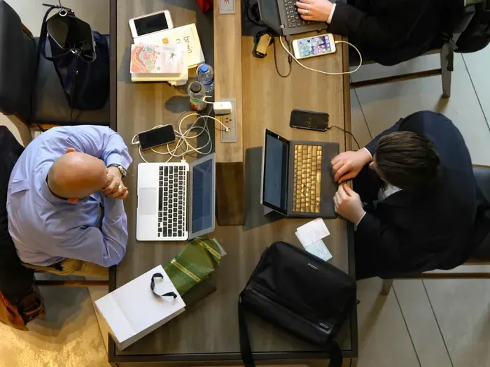Overhead view of two people working at a long table with laptops and papers, City Service Link supports teamwork